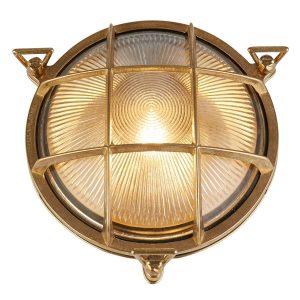 Solid brass round outdoor bulkhead light with ribbed glass shade on white background lit
