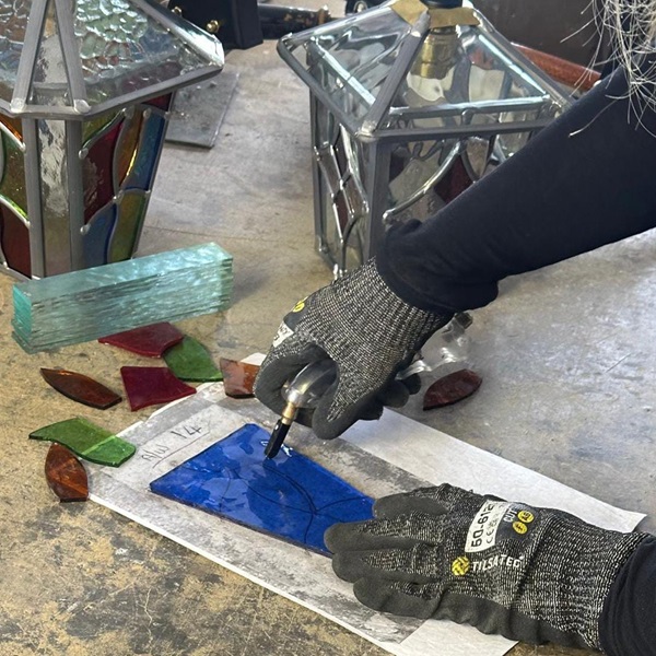 Blue glass being cut by hand over pattern