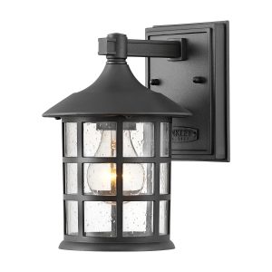 Hinkley Freeport 1 light small outdoor wall lantern in textured black on white background, lit.