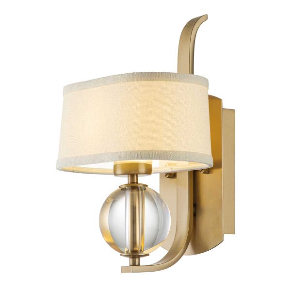 Quoizel Gotham modern wall light in brushed brass on white background, lit