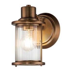 Quoizel Riggs single bathroom wall light in weathered brass on white background lit