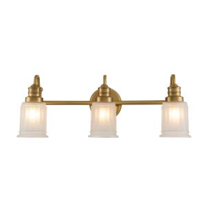 Quoizel Swell 3 light bathroom wall light in brushed brass finish with frosted glass shades on white background lit